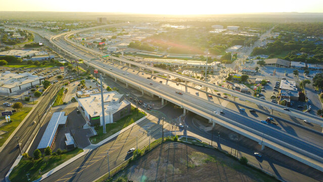 Elevated highway flyover spans, commercial retail plazas border Loop 410 along Evers Road. Sunlit arterial intersections connect regional traffic corridors across San Antonio, Texas