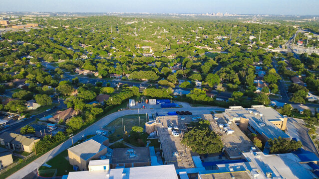 Public school building rooftops, neighborhood residential streets border Evers Road near Loop 410. Educational facilities intersect sprawling suburban tree canopies in San Antonio, Texas