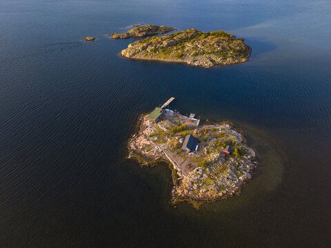 Aerial view of Sando island featuring small wooden cabins and rocky terrain surrounded by the calm blue sea in Vallda, Hallands lan, Sweden.
