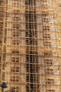 High rise building covered with dense bamboo scaffolding during construction and renovation in Hong Kong city. Traditional building technique contrasts with modern urban development