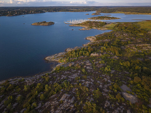 Aerial view of Sando featuring a marina with numerous sailboats, rocky coastal terrain, and surrounding islands in the blue sea, Vallda, Hallands lan, Sweden.