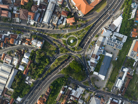 Aerial view of Statue of Dewa Ruci at the center of a busy roundabout surrounded by urban infrastructure, roads, and buildings in Kecamatan Kuta, Bali, Indonesia.