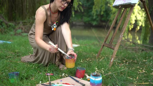 Woman painting outdoors on a canvas and easel and artist palette