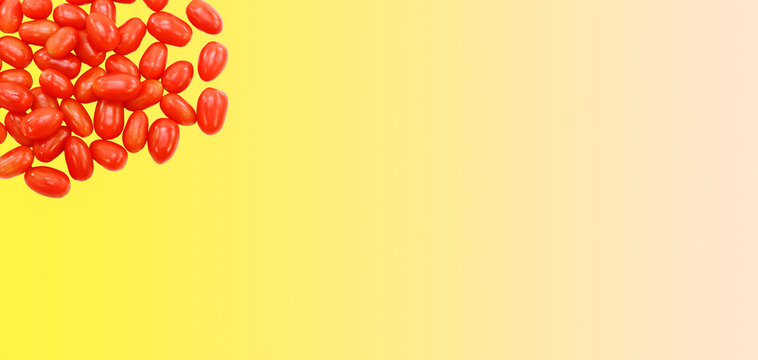 Piccoli pomodori maturi dalla forma allungata ammucchiati su uno sfondo di colore giallo con spazio per testo