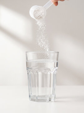 Pouring Scoop of White Creatine Powder into Glass of Water