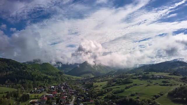 Aerial Hyperlapse of Mountain Village and Clouds Passing Over Green Hills