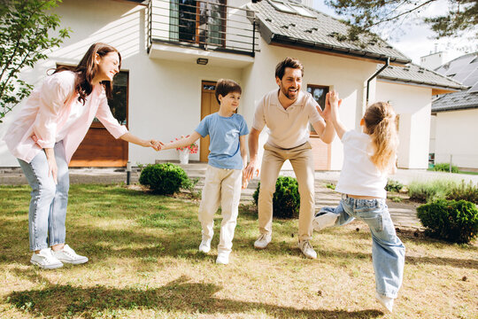 Happy family playing together in front of new home