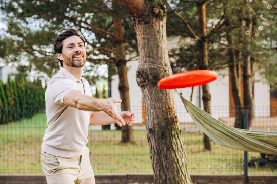 Happy man playing frisbee in backyard, enjoying summer