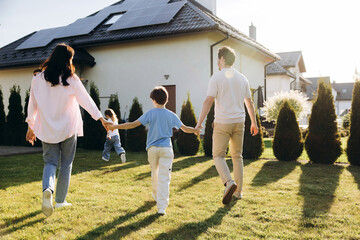 Fototapeta premium Happy family walking in backyard with solar house