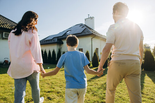 Family walking holding hands towards solar panel house
