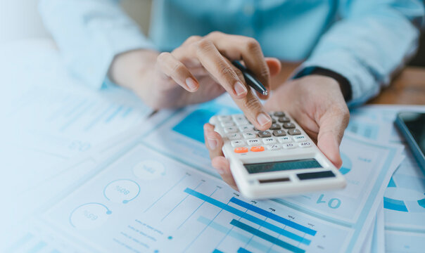 Business report corporate finance and accounting concept, professional hands using calculator with pen analyzing data graph document for budget planning wealth management and economic growth strategy.