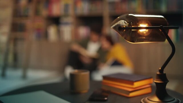 Retro lamp and books on library desk, young couple reads together on the floor