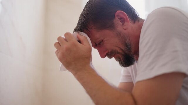 Man straining while sitting on toilet in bathroom, experiencing difficulty with bowel movement and digestive discomfort, representing constipation, stomach pain and gastrointestinal health problems.