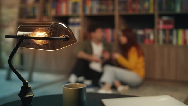 Couple drinks wine and discusses books on library floor, enjoying romantic date