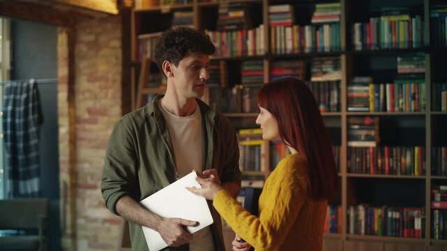 Red-haired female scientist discusses research project with colleague in library