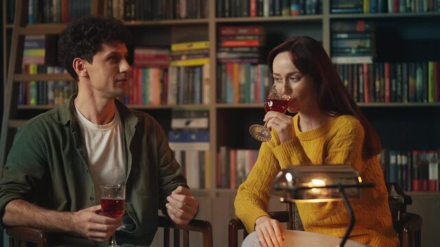 Young red-haired woman and man drink wine during romantic date in coffee shop