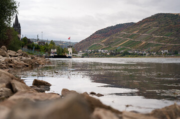Fototapeta premium Ferry on the Rhine beside an exposed rocky riverbank during low water near Niederheimbach and Lorch, Germany