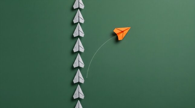 Orange paper plane changing direction from a line of white paper planes representing leadership and standing out concept