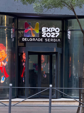 09 August 2026, Belgrade, Serbia: Glass building entrance with Expo 2027 Belgrade Serbia sign and colorful logo. International exhibition, urban branding, and global event representation