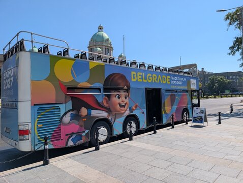 02 August 2026, Belgrade, Serbia: Expo 2027 advertising covers a tour bus parked on a Belgrade boulevard during preparations for the international specialized exhibition.