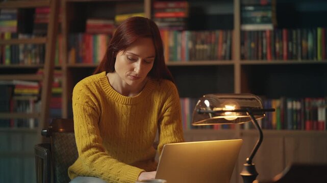 Focused female scientist works on laptop, conducting research in library