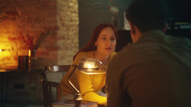 Happy young woman and boyfriend talk while drinking tea together in cozy cafe