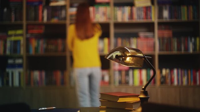 Female student chooses book from university library shelf, enjoying reading