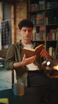 Focused young man reads interesting book in cozy bookshop cafe, enjoying hobby