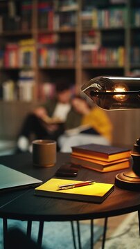 Lamp and books on library desk, romantic couple enjoys reading on the floor