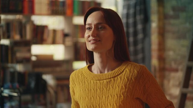 Young red-haired woman waits for date in bookshop cafe, worried he will not come
