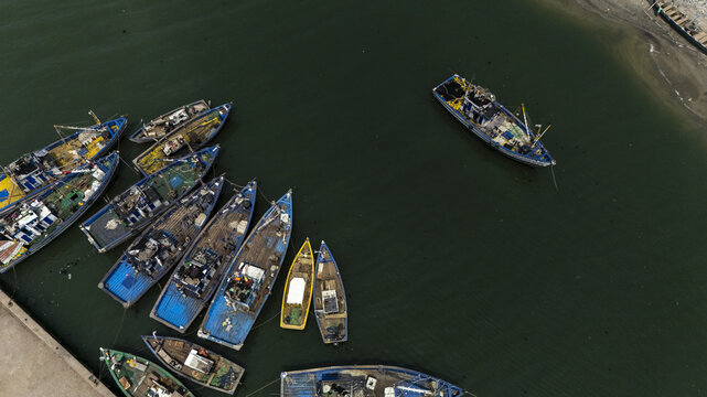 Aerial view of fishing boats moored in the harbor with colorful hulls and nets on deck in Elmina, Central Region, Ghana.