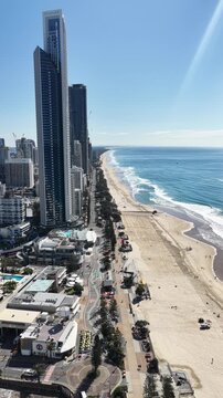 Surfers Paradise coastline from above, surf breaking beside the high-rise strip, Gold Coast, Queensland Australia - vertical video