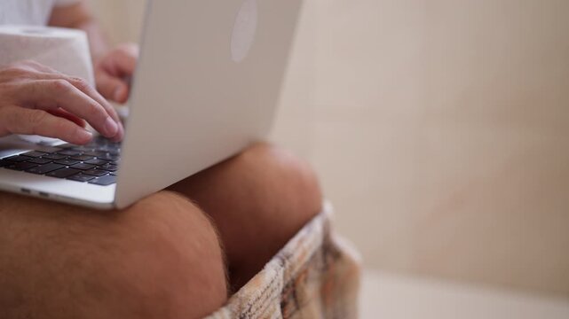 Modern problem of work addiction showing a male businessman with his pants down, sitting on the toilet and typing on his laptop, unable to disconnect from work even in the restroom