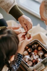 Obraz premium Hands of a young East Asian girl and her grandfather exchanging a wooden ornament, cozy and nostalgic domestic scene for holiday and family campaigns