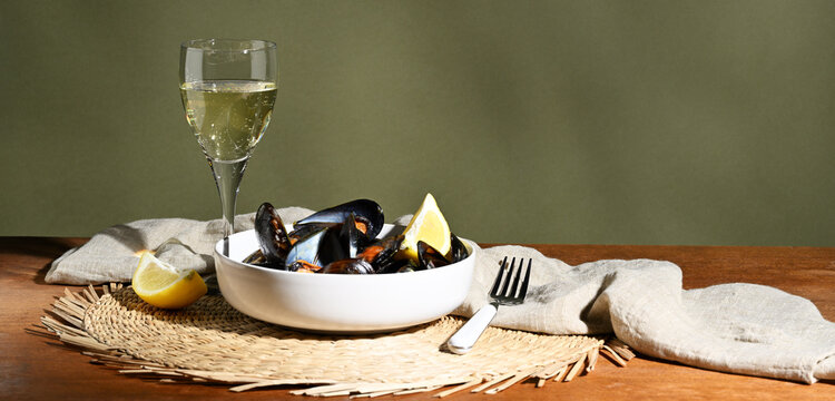 Cooked mussels in a bowl with a glass of wine