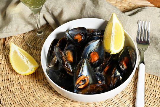 Cooked mussels in a bowl with a glass of wine