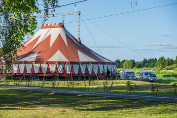Red and white big top circus tent in countryside field © YuraFF