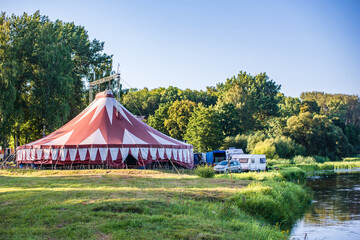 Traditional big top circus tent setup in scenic rural landscape © YuraFF