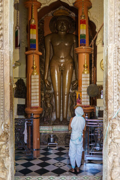 India. Madhya Pradesh. Khajuraho. A worshipper in white ceremonial robes prays before the monumental statue of a Tirthankara at the Shantinath Temple