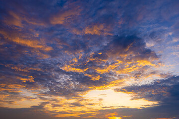 Fototapeta premium Dramatic Golden Sunset Clouds in a Deep Blue Sky,A breathtaking view of the sky during sunset, featuring a vibrant mixture of golden, orange, and dramatic dark blue clouds, creating a serene.