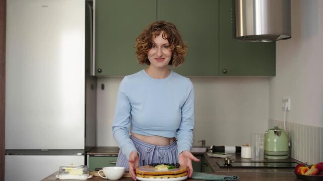 Woman bakes layered sponge cake in sunlit cozy kitchen, 25 fps