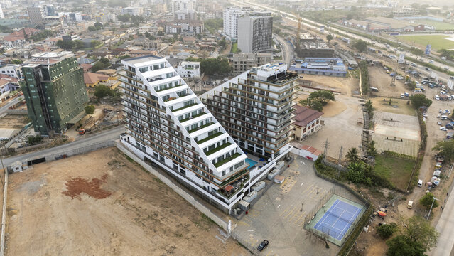 Aerial view of a modern residential complex with stepped architecture, green terraces, and a swimming pool, situated in the urban landscape of Accra, Greater Accra Region, Ghana.