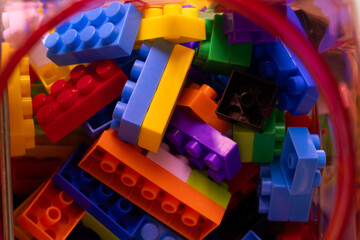 Fototapeta premium Colorful Plastic Building Blocks and Bricks Inside a Container,Macro,Top-down view of a container filled with an assortment of vibrant, multi-colored plastic toy building blocks and bricks, perfect.