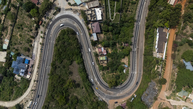 Aerial view of the winding road surrounded by lush tropical vegetation and scattered buildings in Aburi, Eastern Region, Ghana.