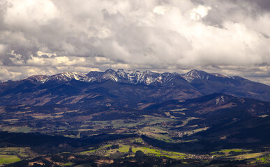 Fototapeta premium Panoramic aerial view of Tatra mountains with snowcapped peaks and valley in Slovakia under cloudy sky