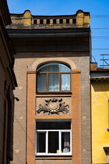 Brick facade of a historic apartment building with arched window © Mariia