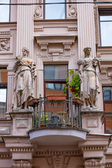 Ornate facade with classical statues flanking an iron balcony © Mariia