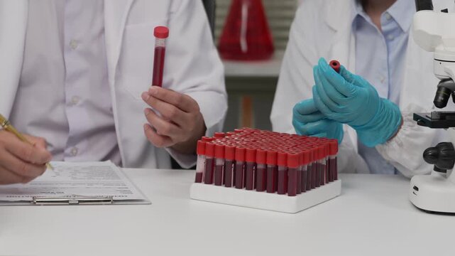 Scientists Hands Holding Blood Sample Vials and Adjusting Microscope in Laboratory