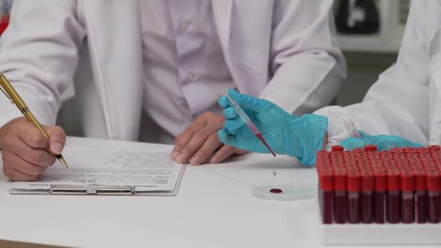 Scientists Hands Holding Blood Sample Vials and Adjusting Microscope in Laboratory