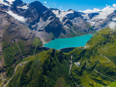 Aerial view of Stausee Mooserboden reservoir nestled among the high alpine peaks of the Hohe Tauern mountains with turquoise water and winding mountain roads Kaprun, Salzburg, Austria.
